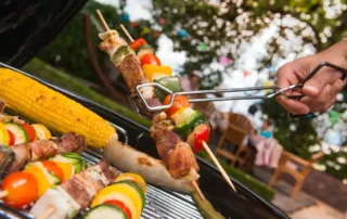 Grill with kabobs on it and other barbecue foods.