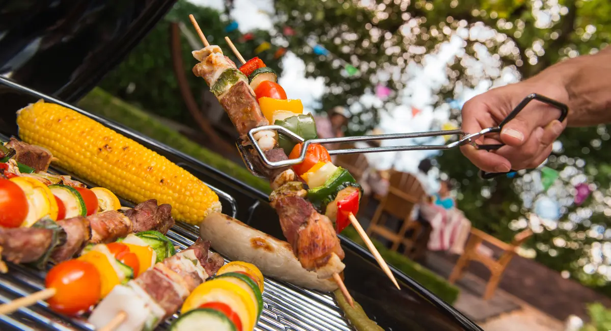 Grill with kabobs on it and other barbecue foods.