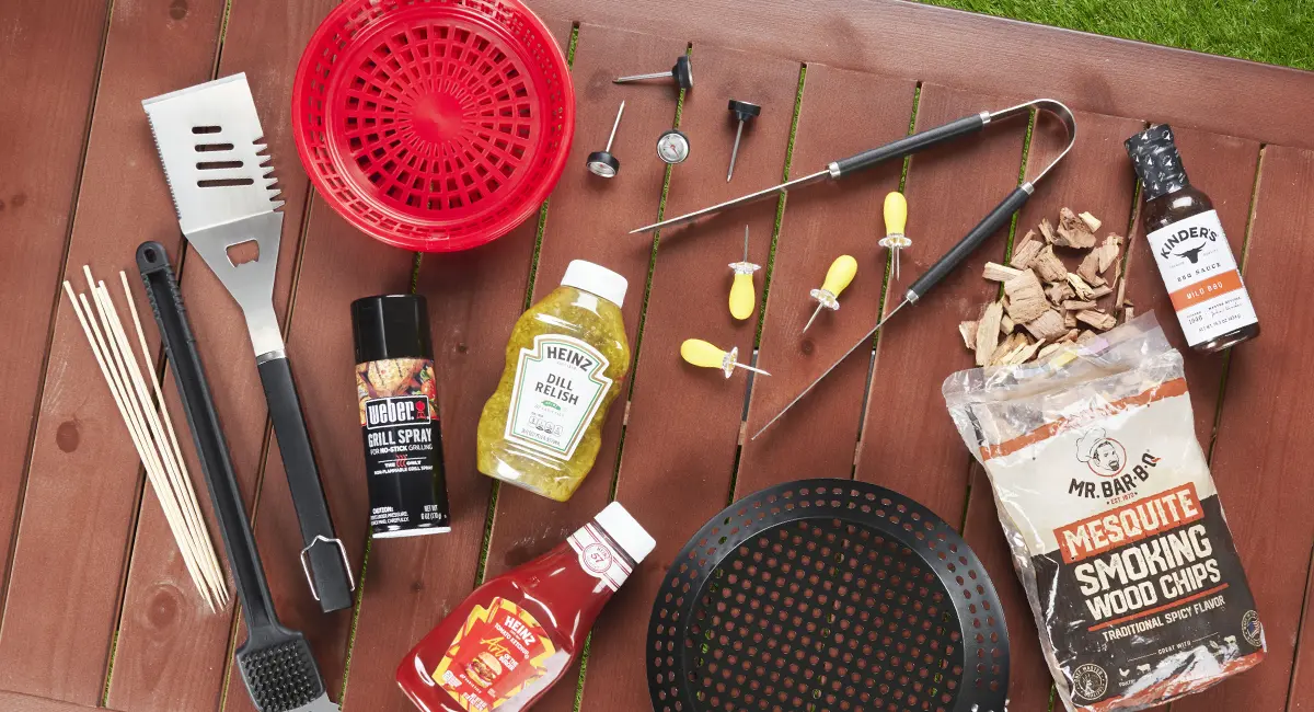 An overhead shot of grill tools on a table in the backyard.