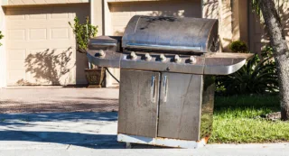 A grill on the sidewalk waiting for pickup on trash day.