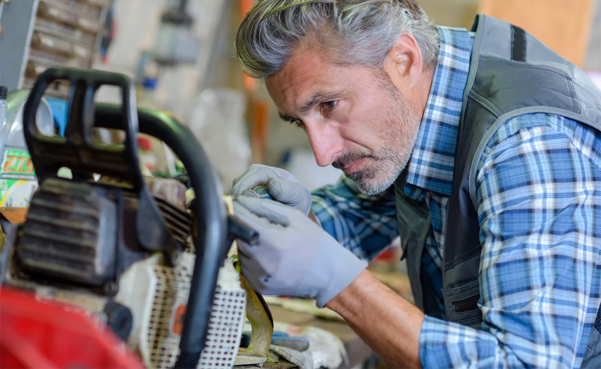 Man working on hedge trimmer in his garage.