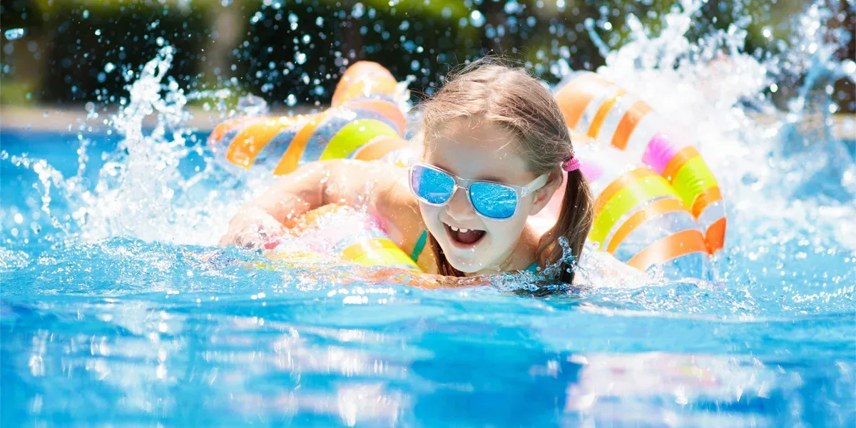 A young girl playing in a tube in her pool in the backyard.