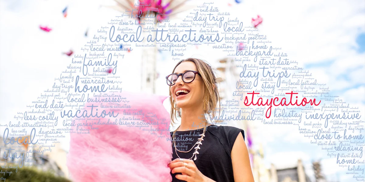 The word staycation in a word cloud over an image of a woman at an amusement park.