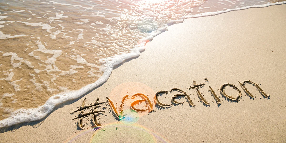 A hashtag of the word vacation in the sand at the beach