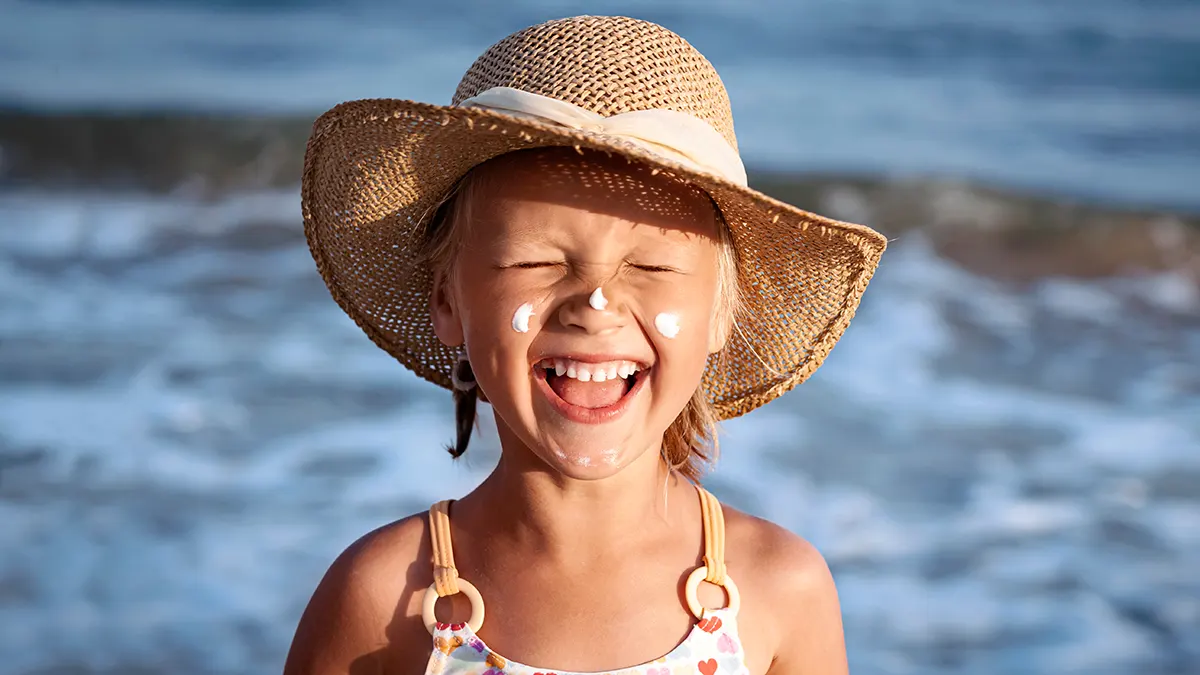 Girl wearing beach hat with sunscreen on her face