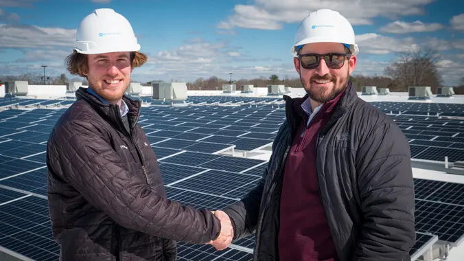 Two men shaking hands on solar roof top