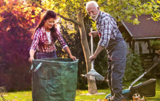 Man and woman raking and bagging autumn leaves.