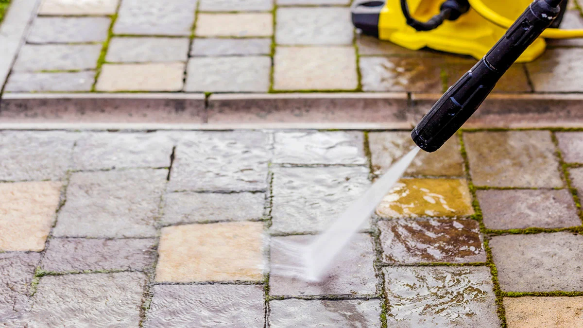 A person cleaning paving stones with pressure washer.