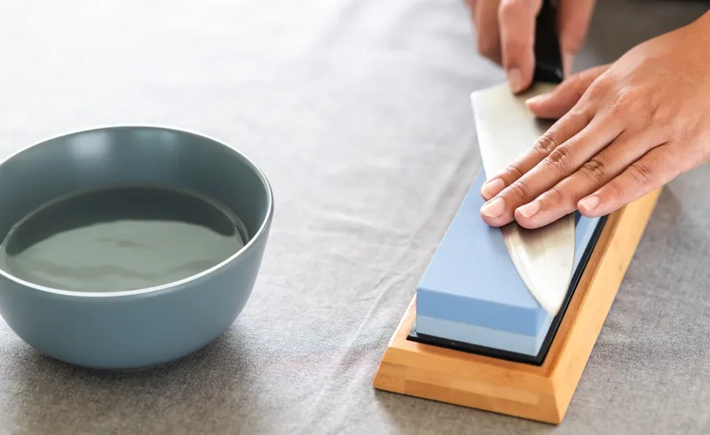 A person sharpens a knife on a whetstone.