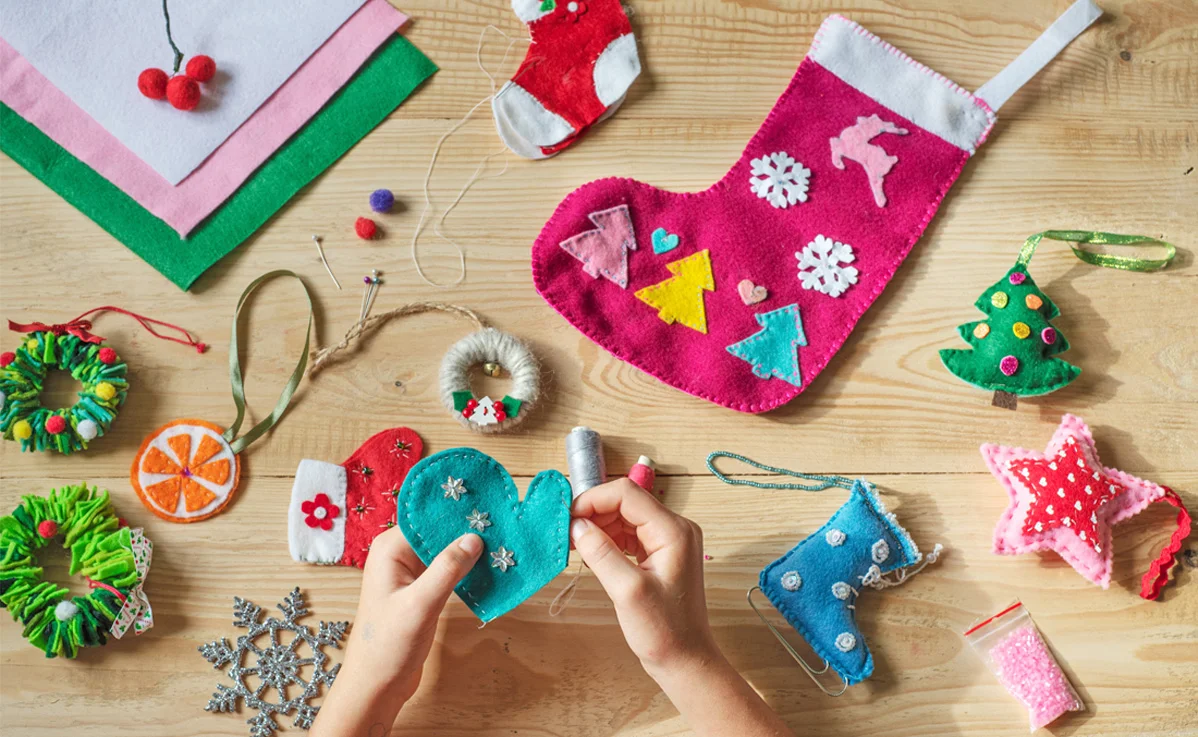 Hand sewing decorations onto Christmas stocking using needle and thread.