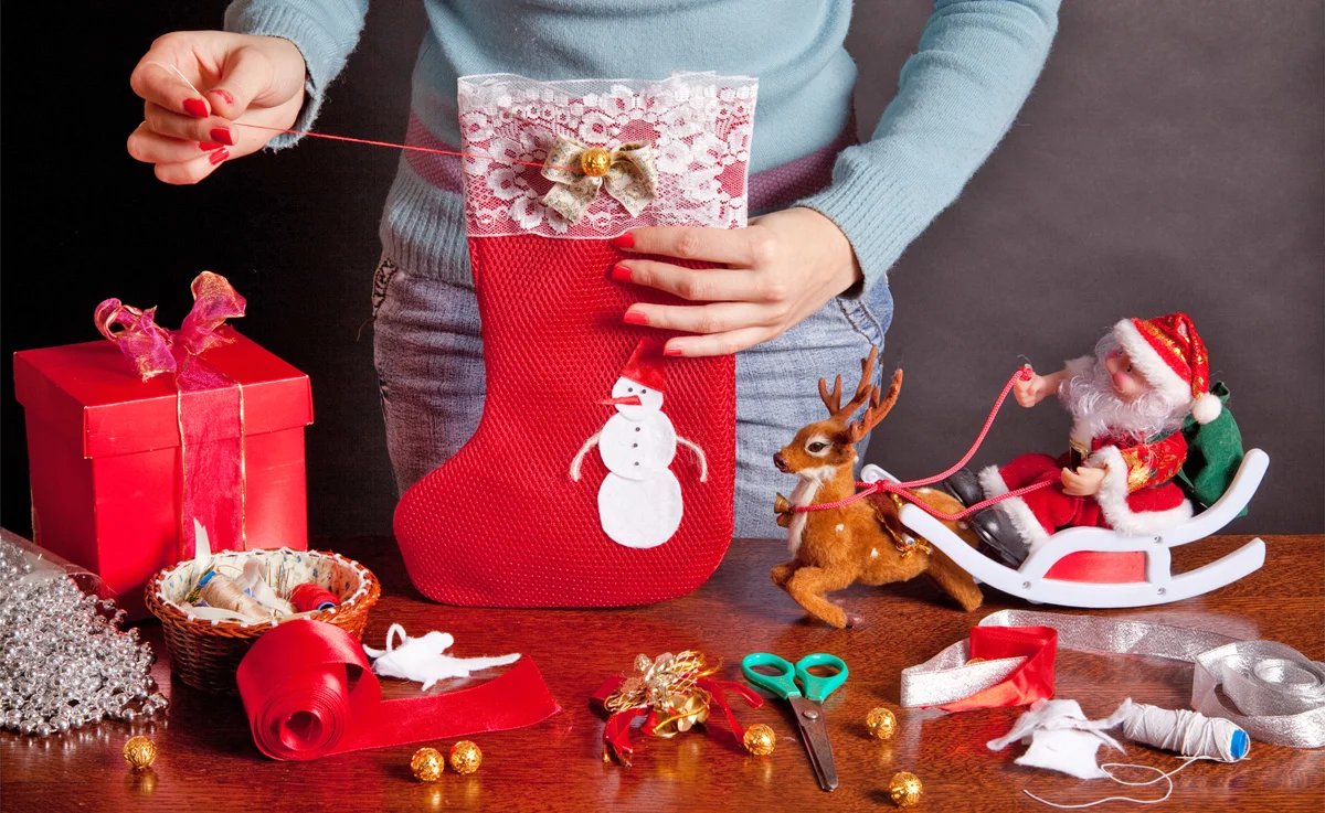 Sewing decorations onto the top of Christmas stocking.