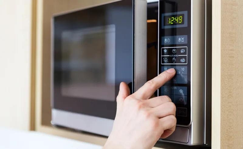 A person uses a microwave.