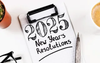 A clipboard with a written note that reads "2025 New Year's Resolutions"