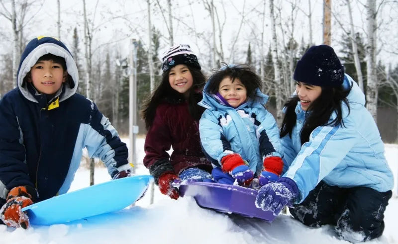 a family sledding outside in the snow