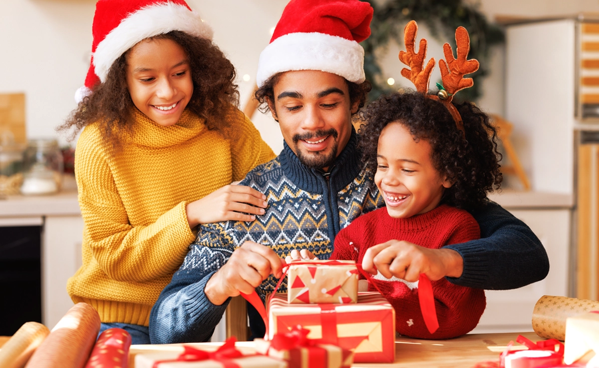 Father and daughters wrap Christmas presents together