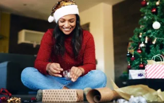 Woman on floor wrapping Christmas presents.