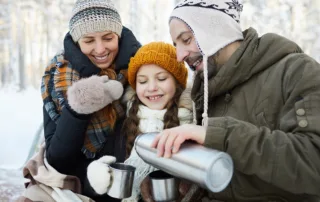 A family enjoys a warm drink outside.