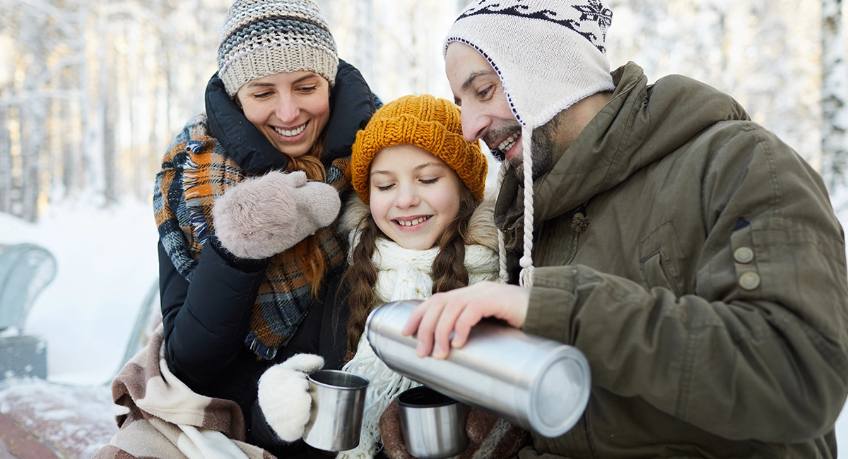 A family enjoys a warm drink outside.