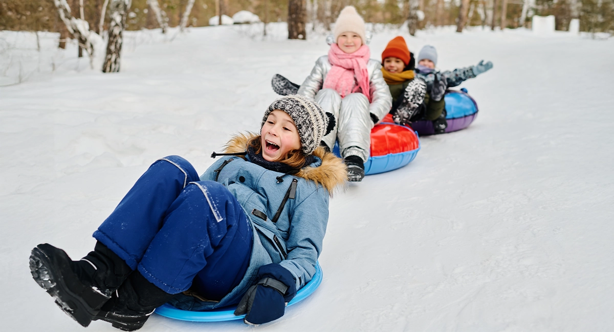 4 kids riding snow tubes in the snow.