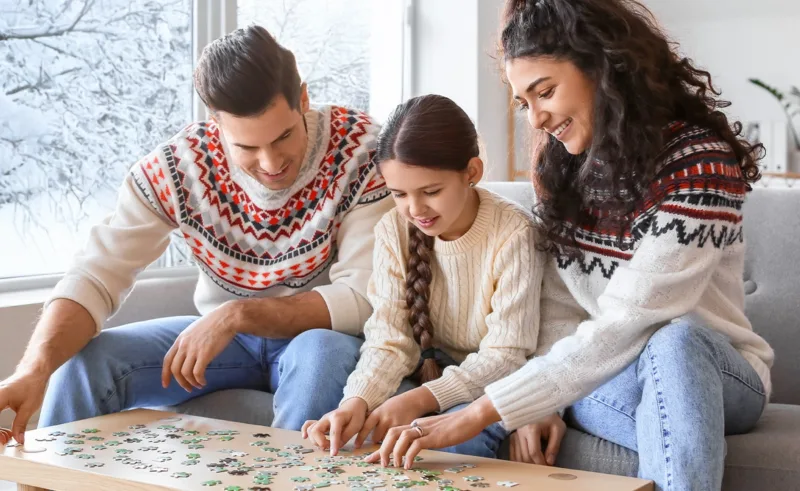 A family does a puzzle while it snows outside.