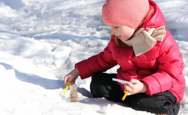 A child doing a science experiment with snow.