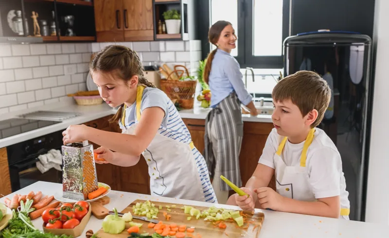 A mother and two children cooking and eating healthier in the kitchen.