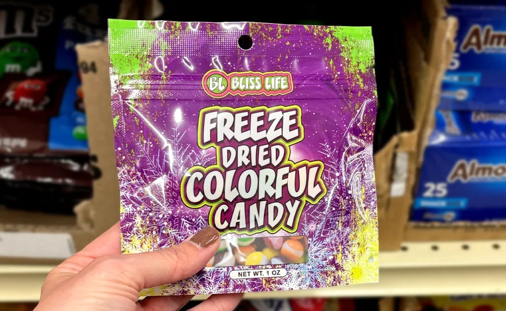 A hand holds up a bag of freeze dried colorful candy.