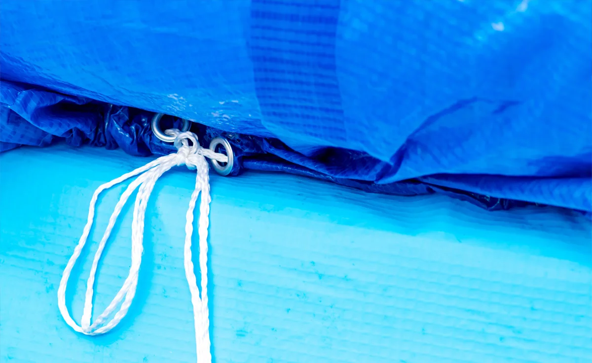 A pool cover tied to the edge of a pool.