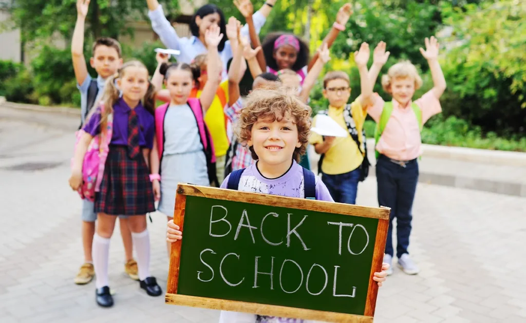 Little kids holding chalkboard that reads "BACK TO SCHOOL"