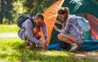 A young couple setting up a tent camping outdoors.