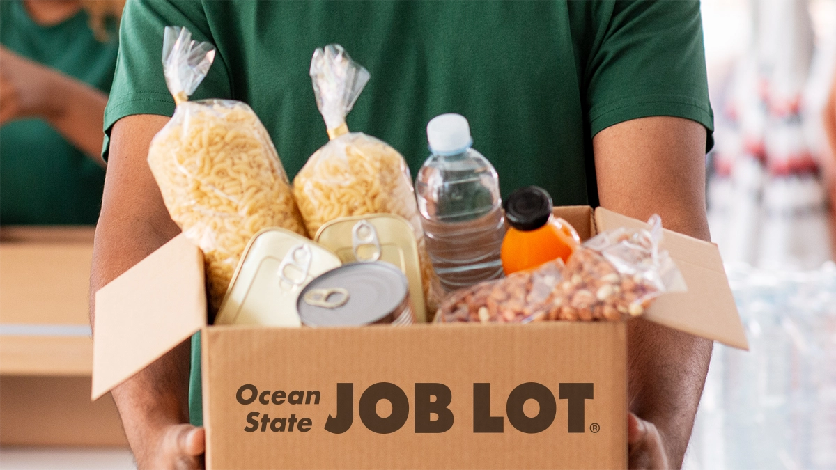 Person holding a box of food donations and the box has Ocean State Job Lot label on the front