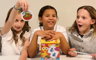 Three young girls unboxing a mystery toy box from Ocean State Job Lot